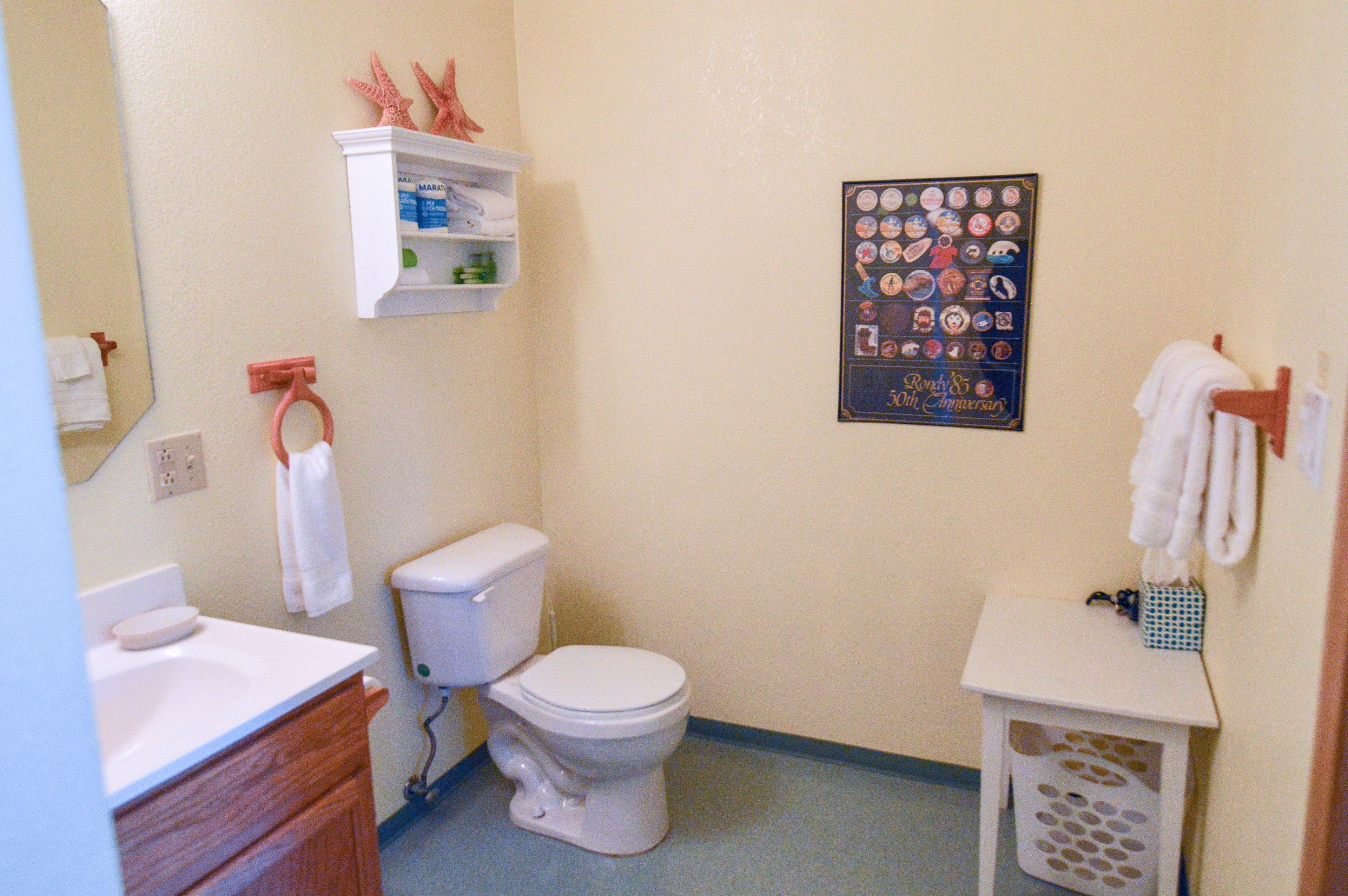 A bathroom with a toilet, sink, and a small shelf with toiletries.