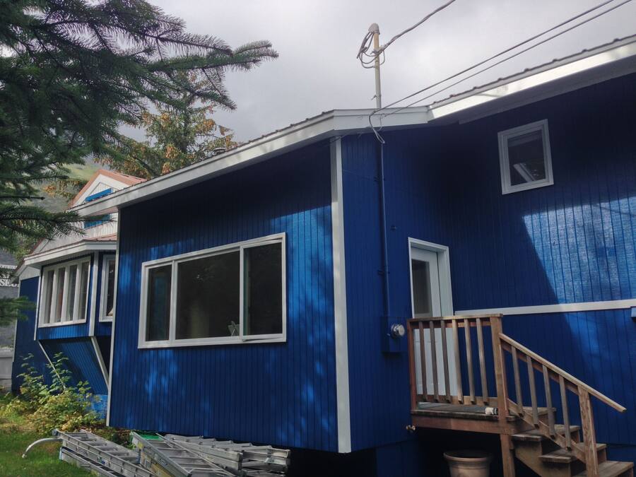 Een blauw huis met een houten trap naar een terras.