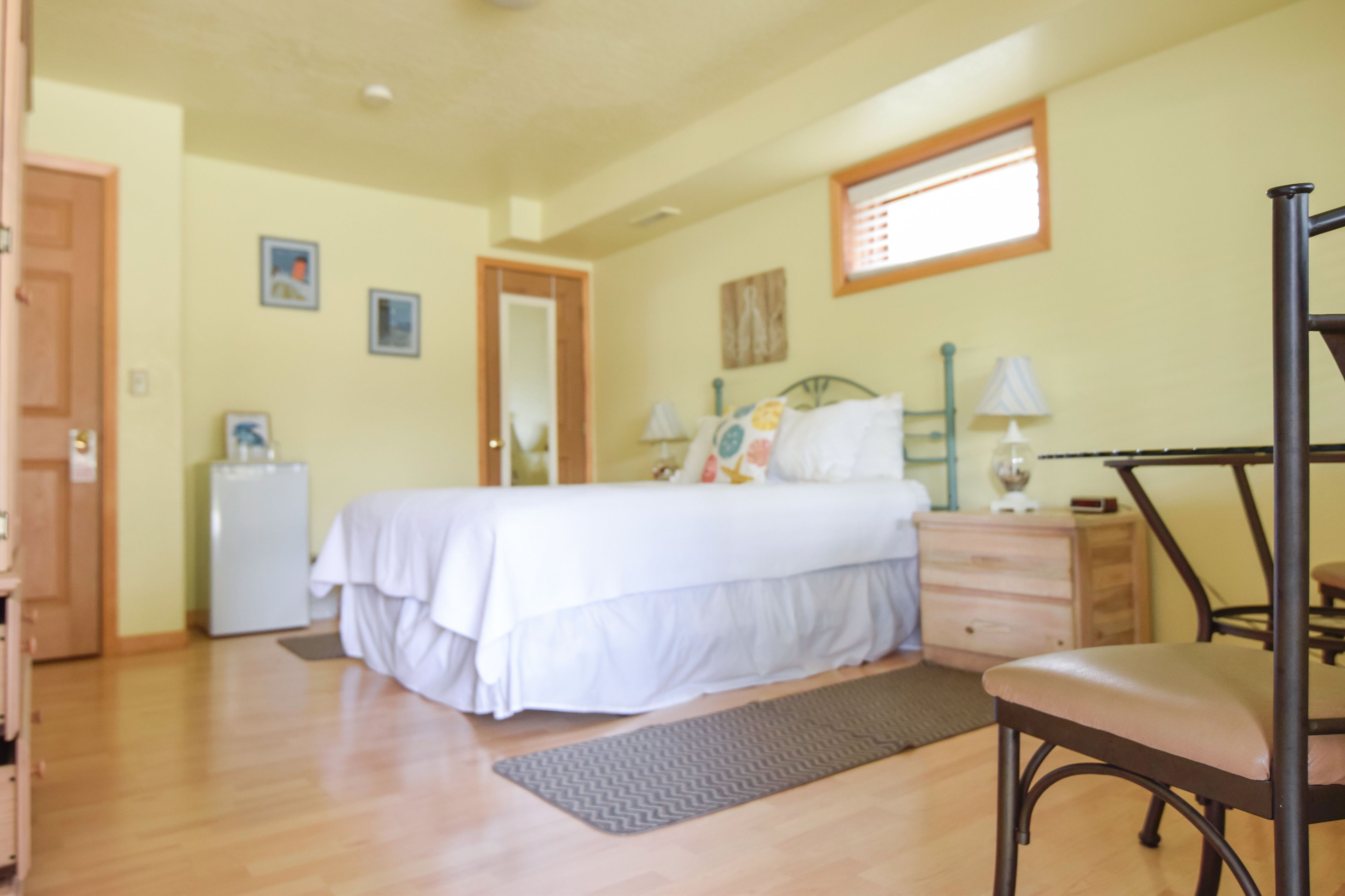 Un dormitorio con cama, mesita de noche, silla y escritorio con lámpara.