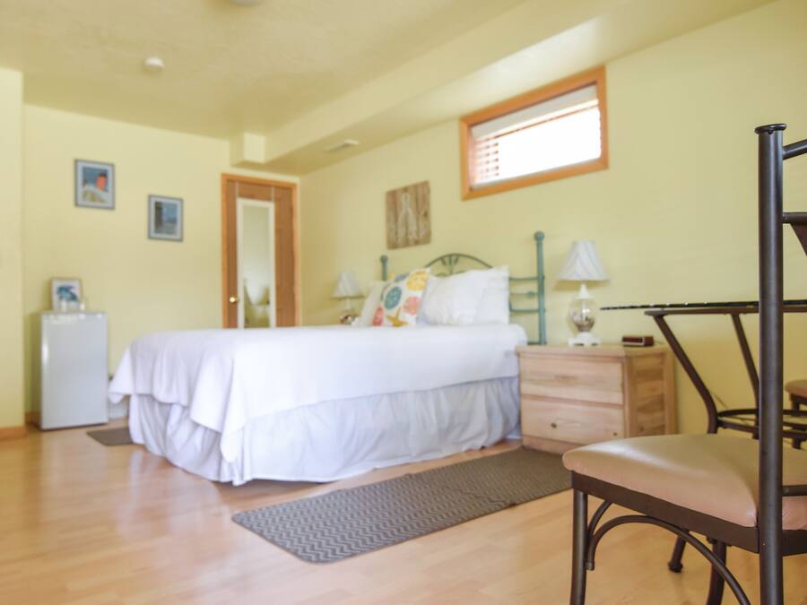 Un dormitorio con cama, mesita de noche, silla y escritorio con lámpara.