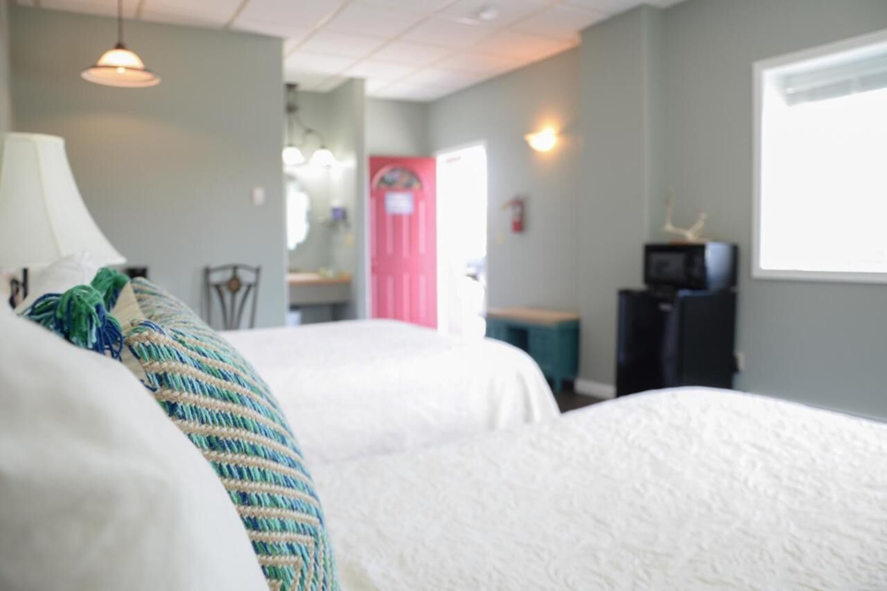 A hotel room with two beds, a desk, a chair, a television, and a window.