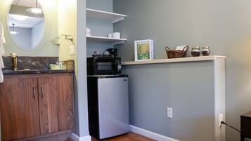 A compact kitchen with a microwave, refrigerator, and wooden cabinets.