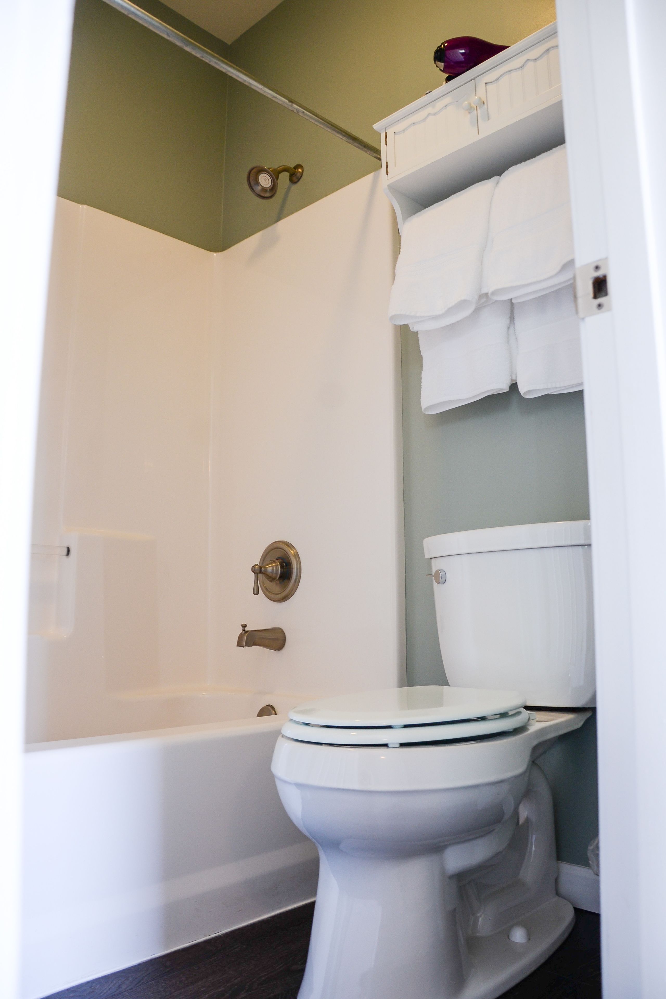 A bathroom with a white bathtub, a toilet, and a shower curtain.