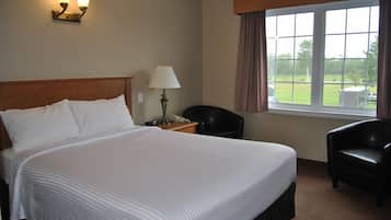 Una camera d'albergo con un letto grande, un comodino con una lampada, una sedia e una finestra con tende.