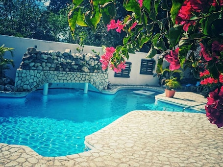 Una piscina al aire libre, sillones reclinables de piscina
