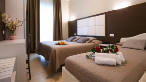 Une chambre d’hôtel avec deux lits, une télévision, un bureau et une fenêtre avec des rideaux.