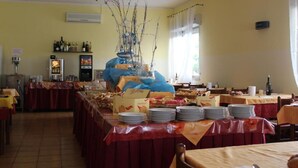 Un espace repas avec des tables dressées pour le service, un bar avec des bouteilles exposées et une plante décorative en guise de centre de table.