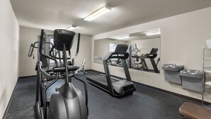 A gym with cardio equipment, a treadmill, and a mirrored wall. - Risewell Kitchen Suites Pleasanton (Pleasanton)