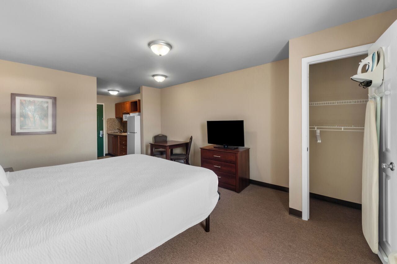 Une chambre d’hôtel avec un grand lit, un bureau, une télévision et un dressing.