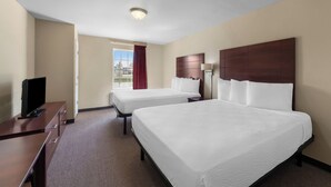 A hotel room with two beds, a desk, a TV, and a window with a view. - Risewell Kitchen Suites Pleasanton (Pleasanton)