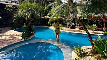 Una piscina al aire libre, sombrillas, tumbonas