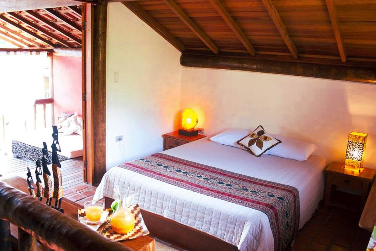 A bedroom with a bed, bedside lamps, a wooden headboard, and a view of the outside.