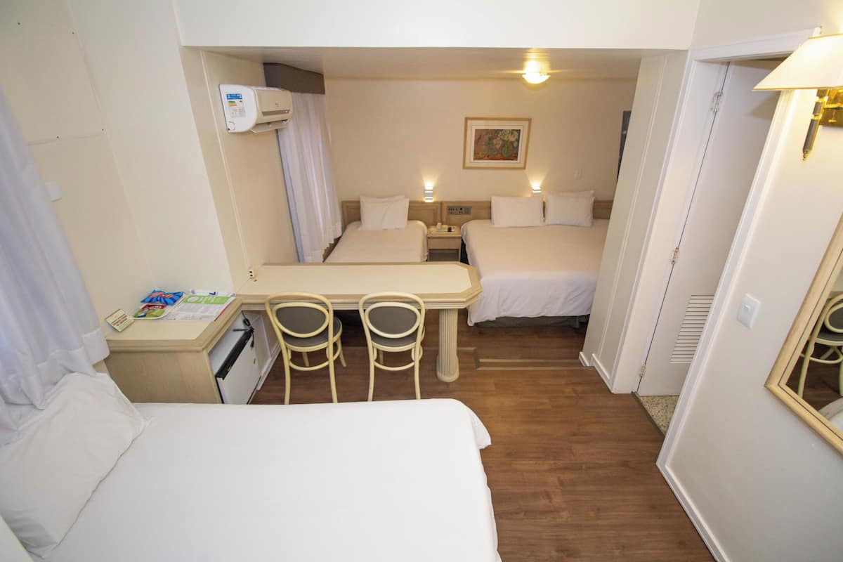 Une chambre d’hôtel avec deux lits, un bureau, des chaises et une petite table.