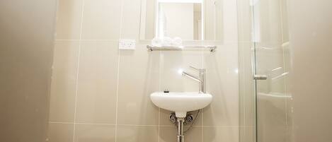 A bathroom with a white sink, a mirror, and a glass shower enclosure.