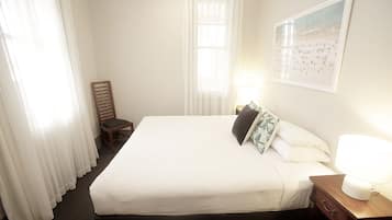 A hotel room with a large bed, a nightstand with a lamp, a chair, and a painting on the wall.