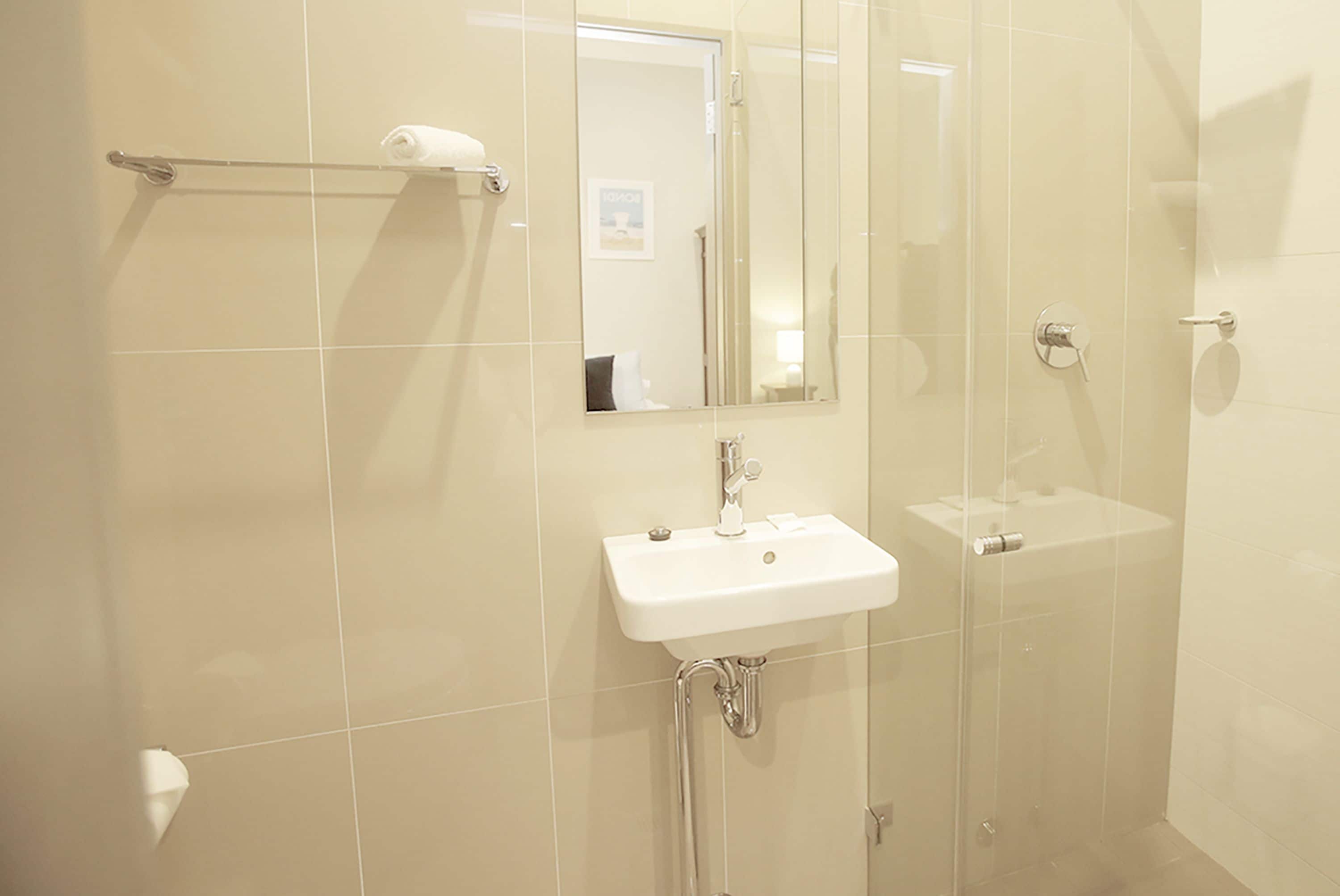 A bathroom with a white sink, a glass shower enclosure, and a towel rack.