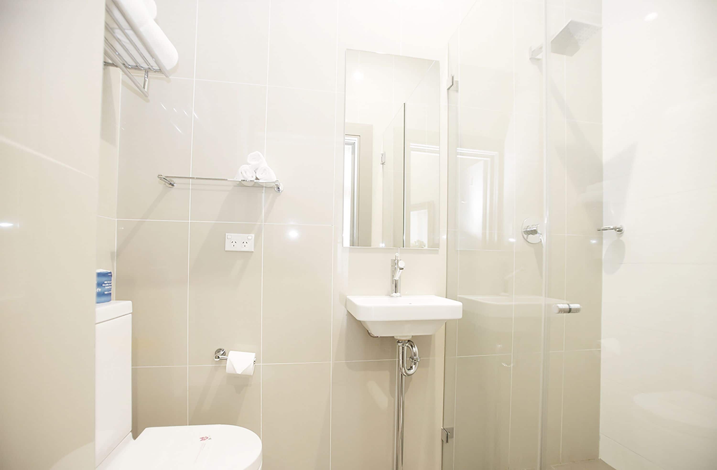 A modern bathroom with a toilet, sink, and glass shower enclosure.