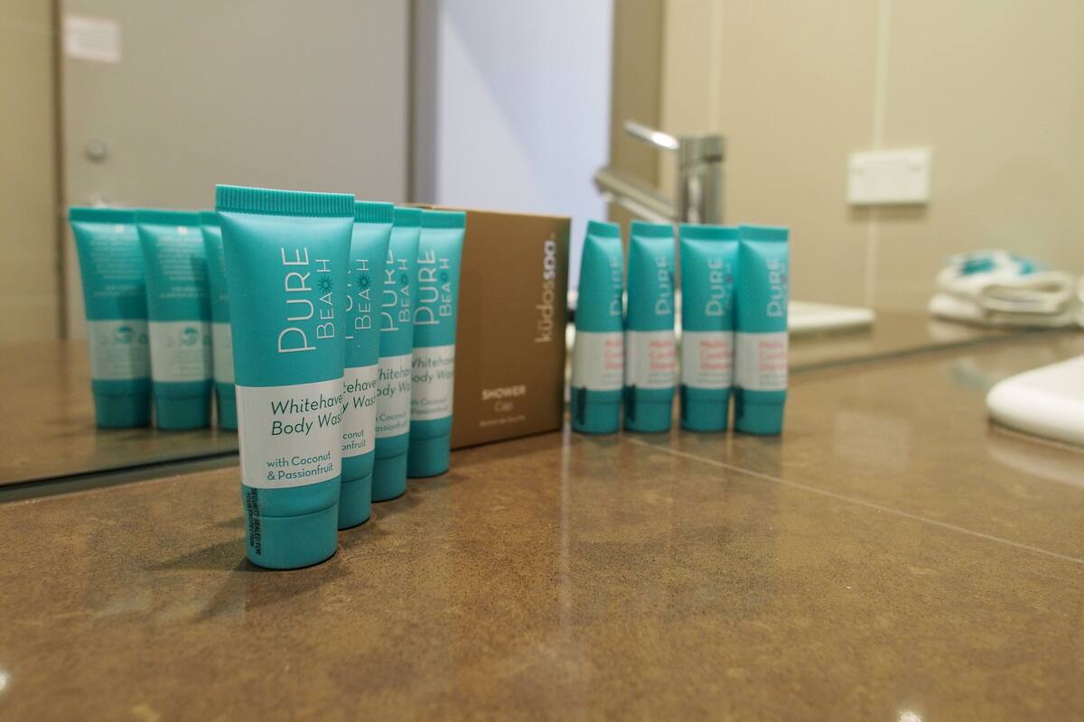 A row of white and teal body wash bottles labeled "Pure Beach" on a bathroom counter.