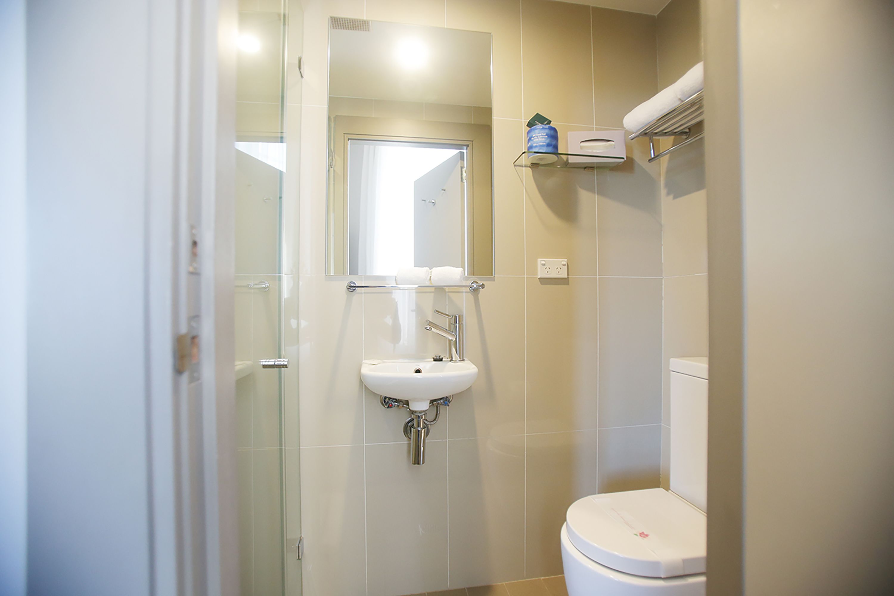 Un baño con cabina de ducha de vidrio, un lavamanos blanco y un inodoro.