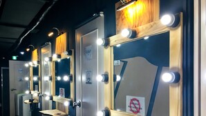 A row of hotel bathrooms with vanity mirrors, lights, and a sign prohibiting hair dryer use. - Philstay Ehwa Boutique (Seoul)