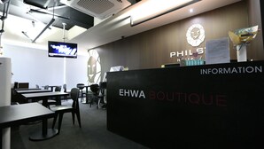 A reception area with a modern design, featuring a black reception desk, a mounted television, and a wall-mounted logo. - Philstay Ehwa Boutique (Seoul)