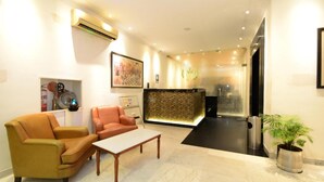 A modern lobby with a reception desk, leather sofas, a coffee table, and a potted plant. - Hotel Yulia (Jaipur)