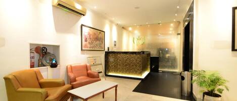 A modern lobby with a reception desk, leather sofas, a coffee table, and a potted plant.