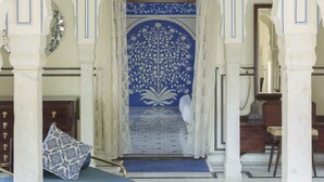 Une pièce richement décorée, avec une porte bleue à motifs, des colonnes blanches et un canapé bleu.