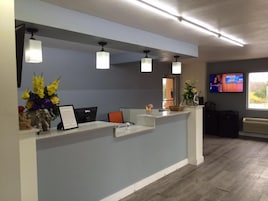 A reception desk with a flat-screen TV, a desk lamp, and a vase of flowers.