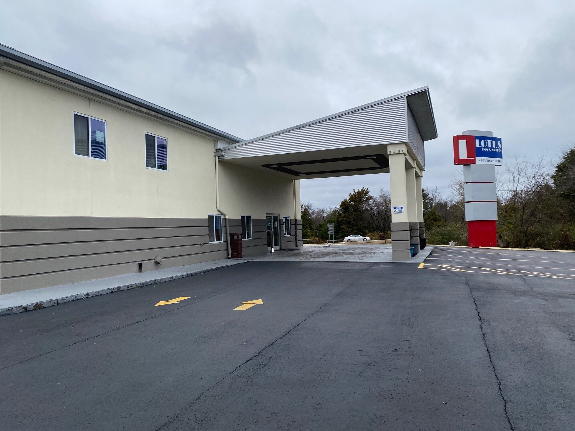 A hotel with a gas station attached, featuring a covered entrance and a visible car in the background.