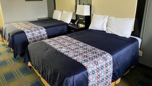 A hotel room with two beds, each with a headboard, a nightstand with a lamp, and a wall-mounted picture.