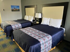 A hotel room with two beds, each with a headboard, a nightstand with a lamp, and a wall-mounted picture.