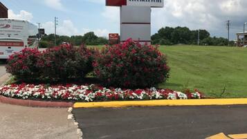 Letrero de LOTUS INN & SUITES con un jardín de flores rojas y blancas al frente.