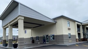 A building with a covered entrance, a staircase, and a parking lot.