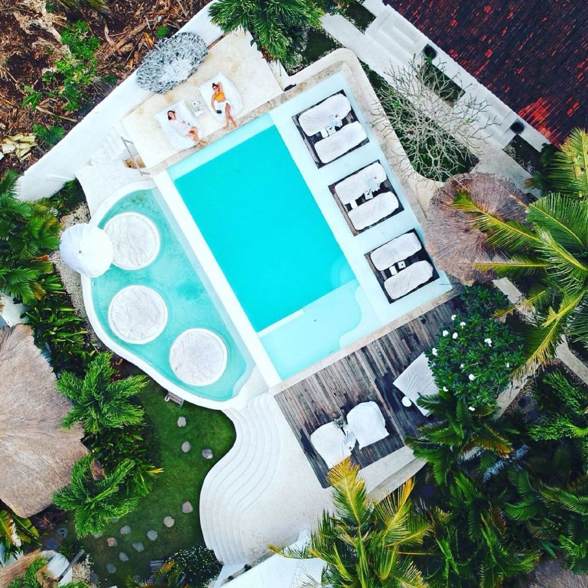 Een zwembad op het dak met ligbedden en een kleine jacuzzi.