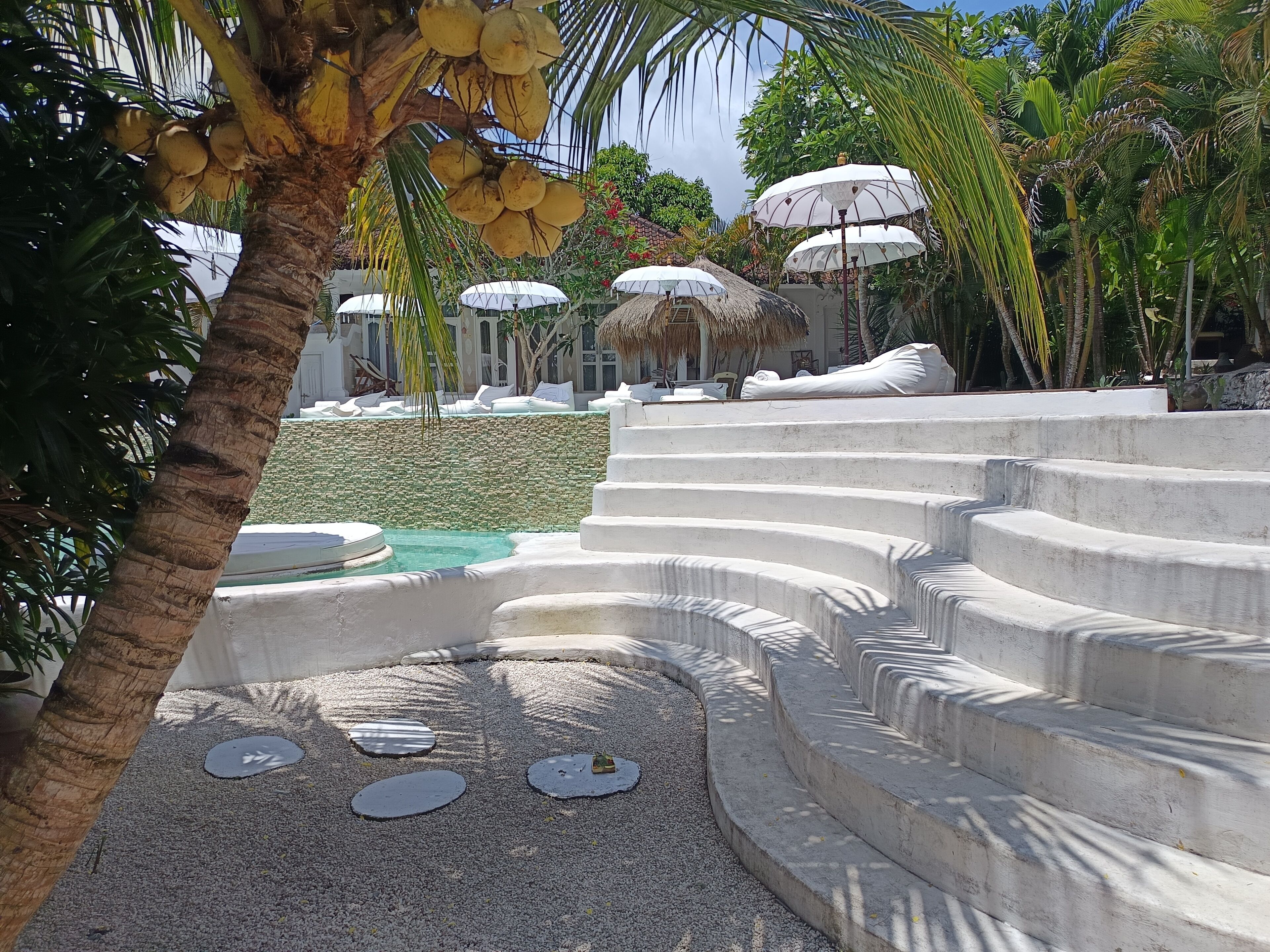 Un resort con piscina, palme e capanne con tetto di paglia.