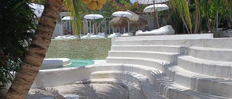 Un resort con piscina, palme e capanne con tetto di paglia.