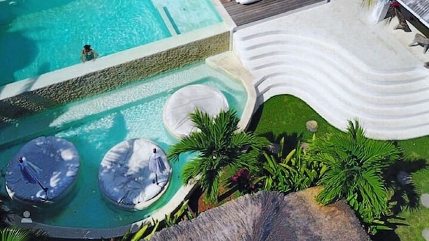 A pool area with lounge chairs, umbrellas, and a water slide. - Sal Secret Spot (Pecatu)
