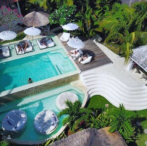 Zona de piscina con sillas de descanso, sombrillas y un tobogán.