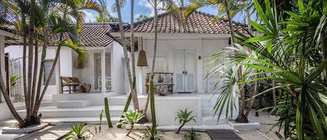 Un resort tropical con un edificio blanco, terraza de madera y palmeras.