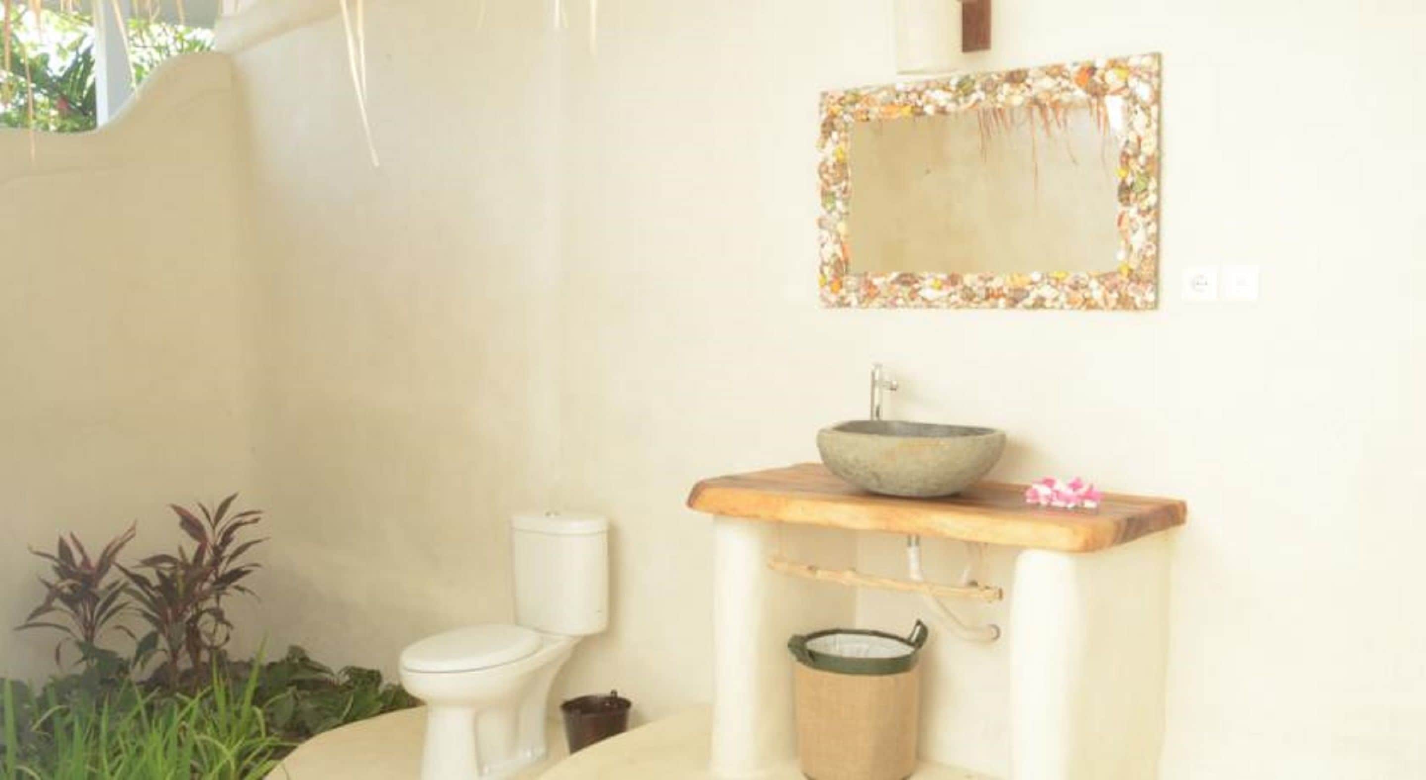 Een badkamer met een toilet, een wastafel met een stenen kom en een houten aanrechtblad.