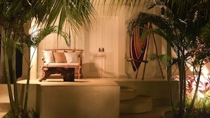 A cozy room with a wooden bed, a small table, and a decorative shield on the wall. - Sal Secret Spot (Pecatu)