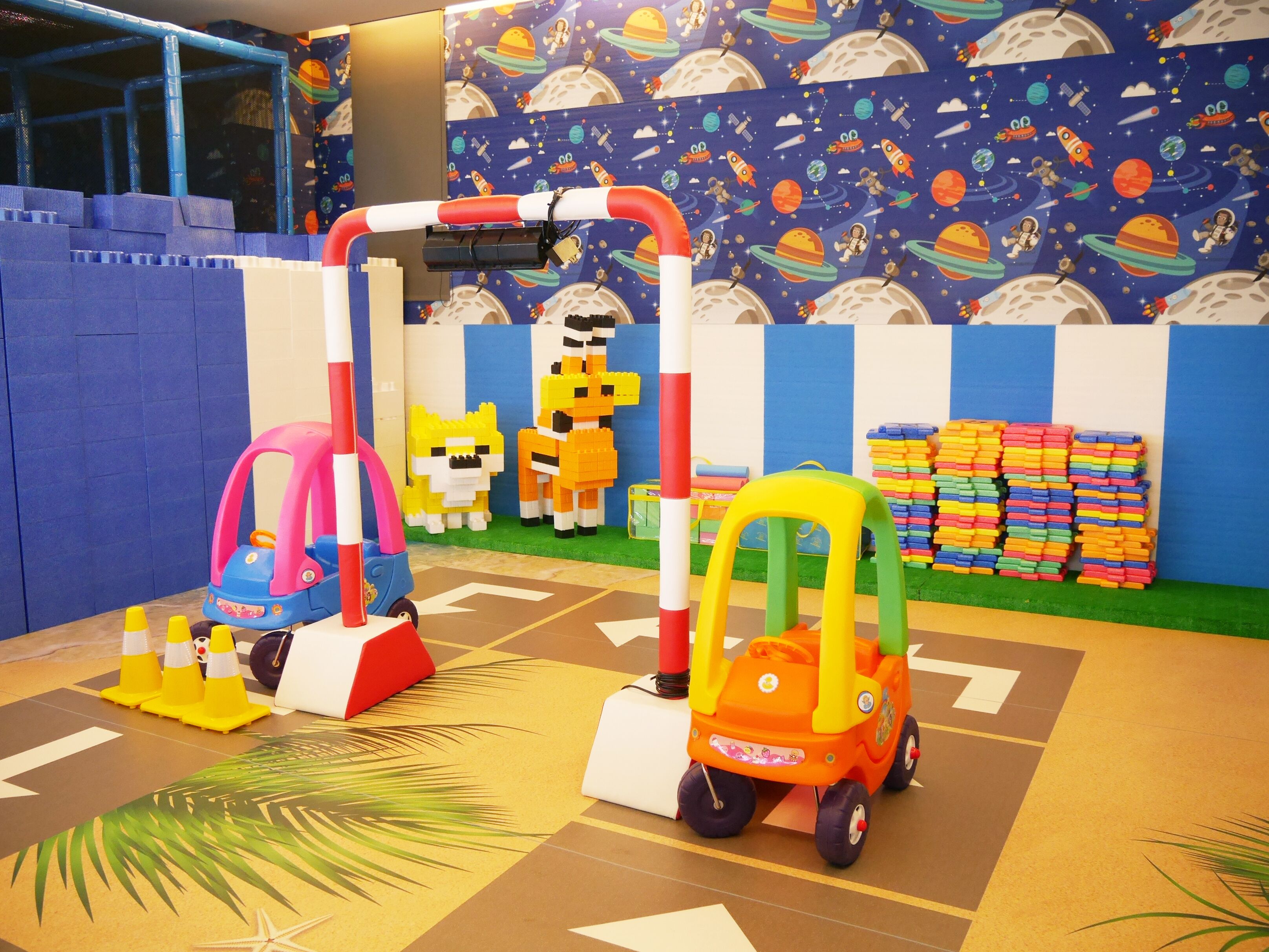 A play area with a space-themed wall, a climbing structure, and colorful toys.