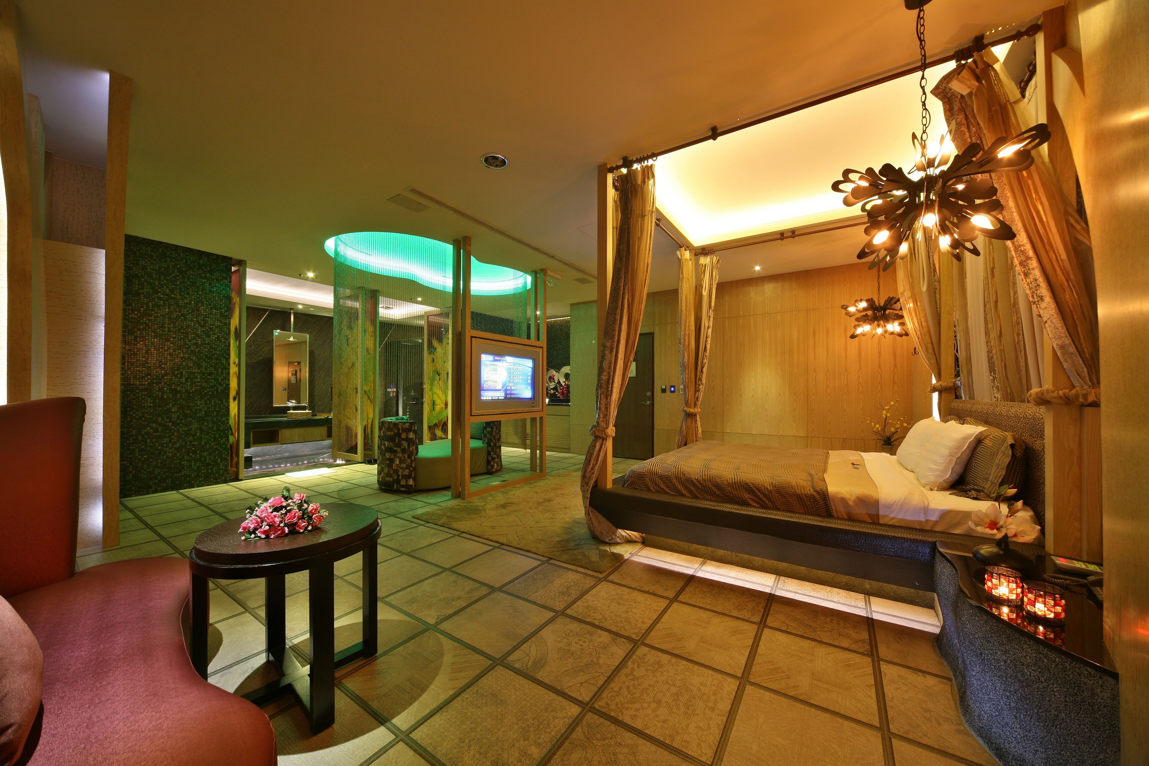 A modern bedroom with a canopy bed, a television, and a small table with flowers.