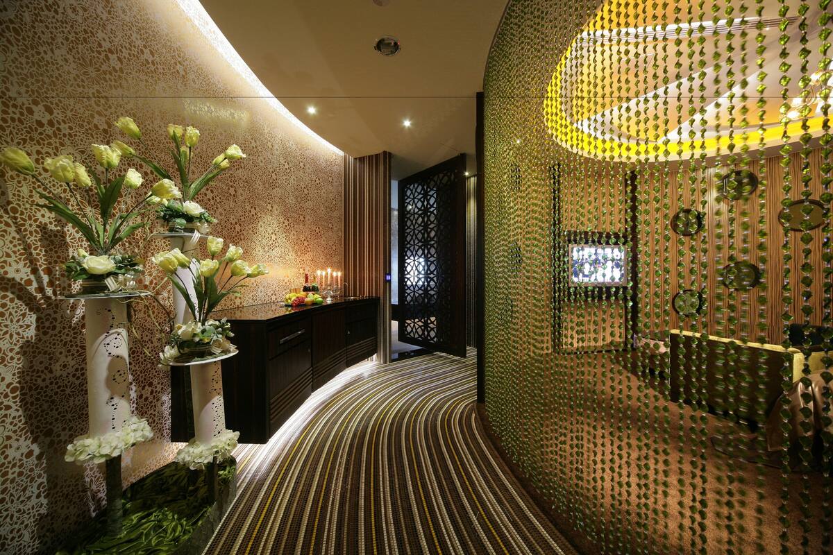 Un interior moderno con un sendero curvo, paneles decorativos en la pared y una zona de recepción con mostrador y plantas.
