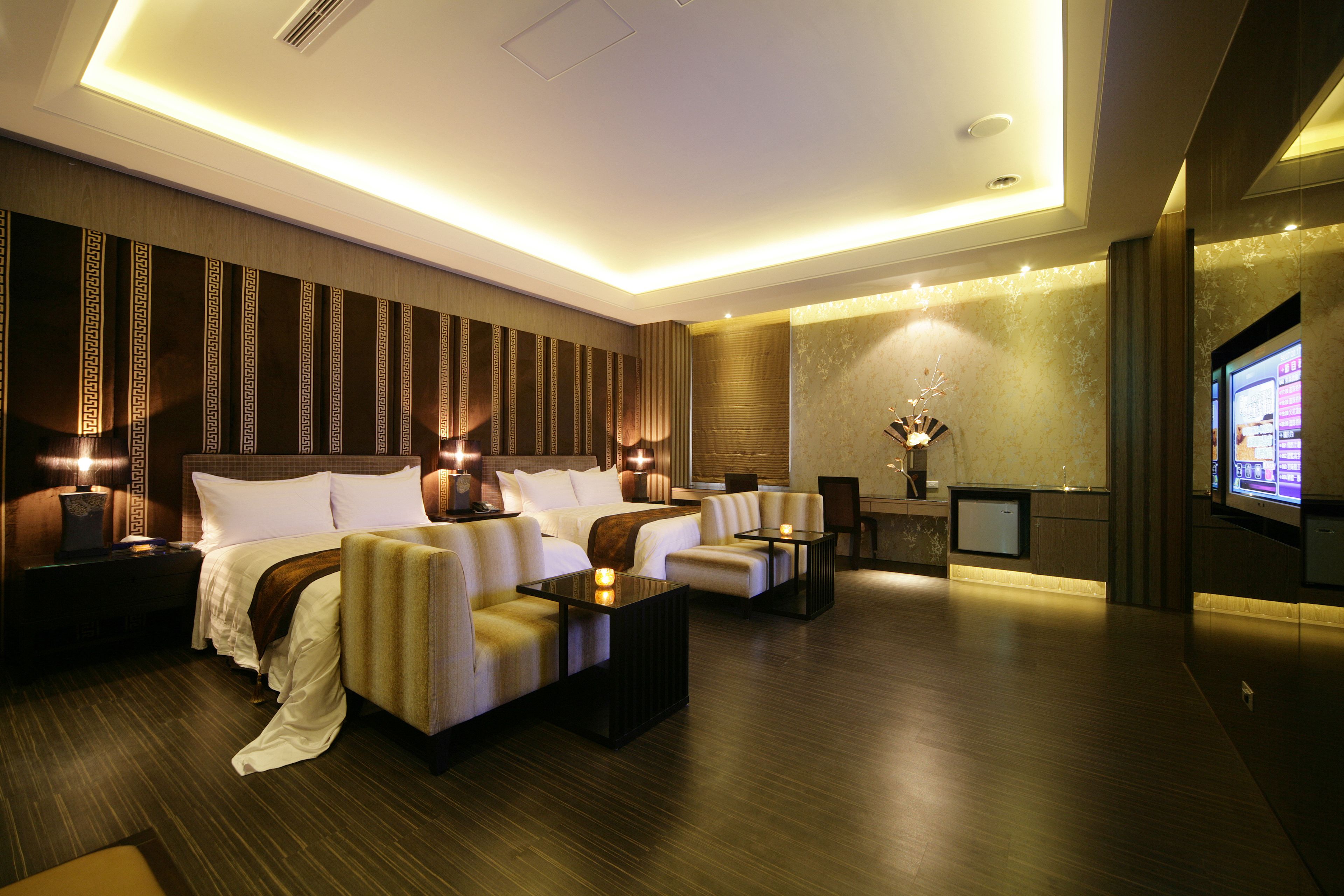 A modern hotel room with a large bed, two sofas, a small table, and a TV.