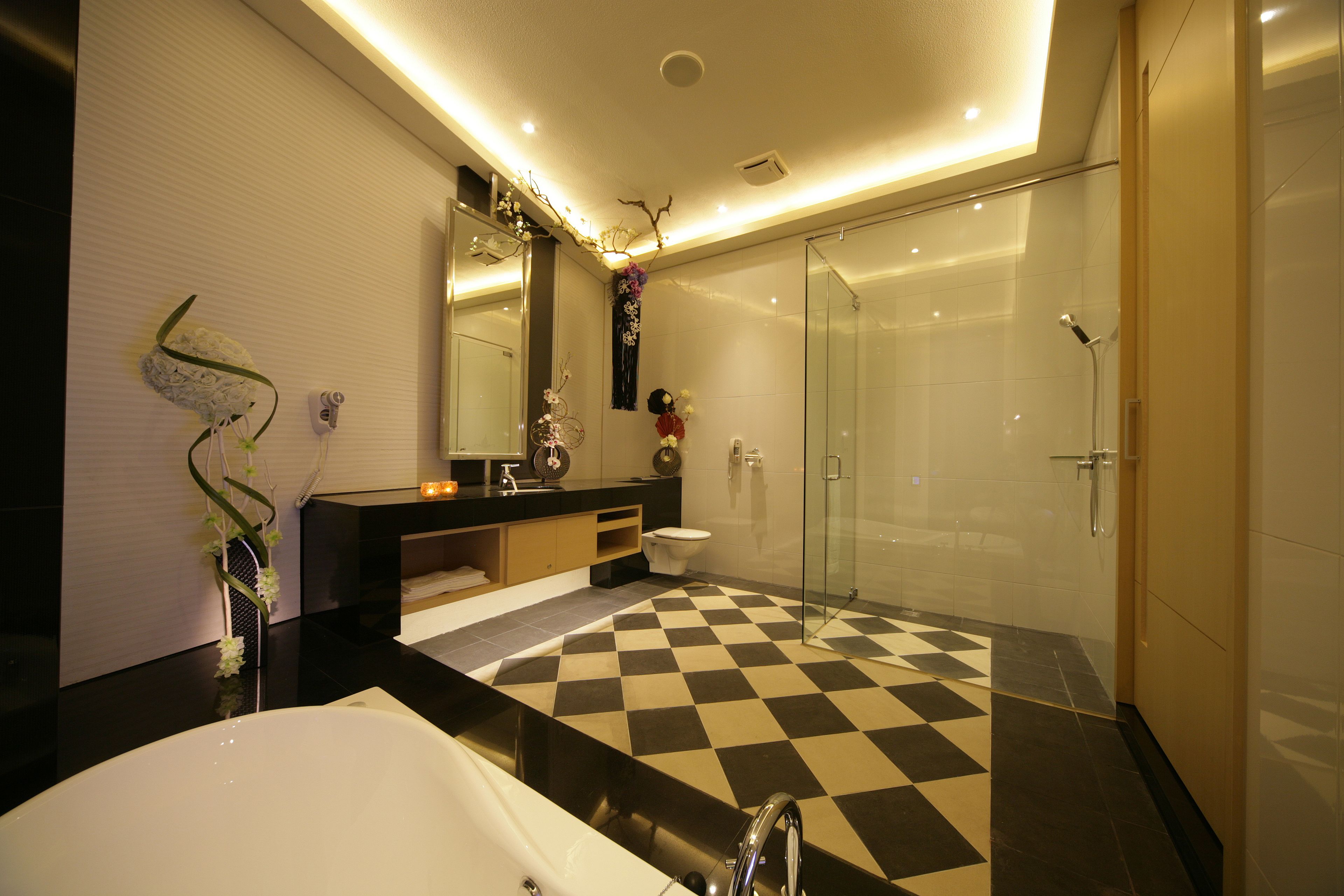 A modern bathroom with a checkered floor, a large bathtub, a glass shower enclosure, and a vanity with a mirror.