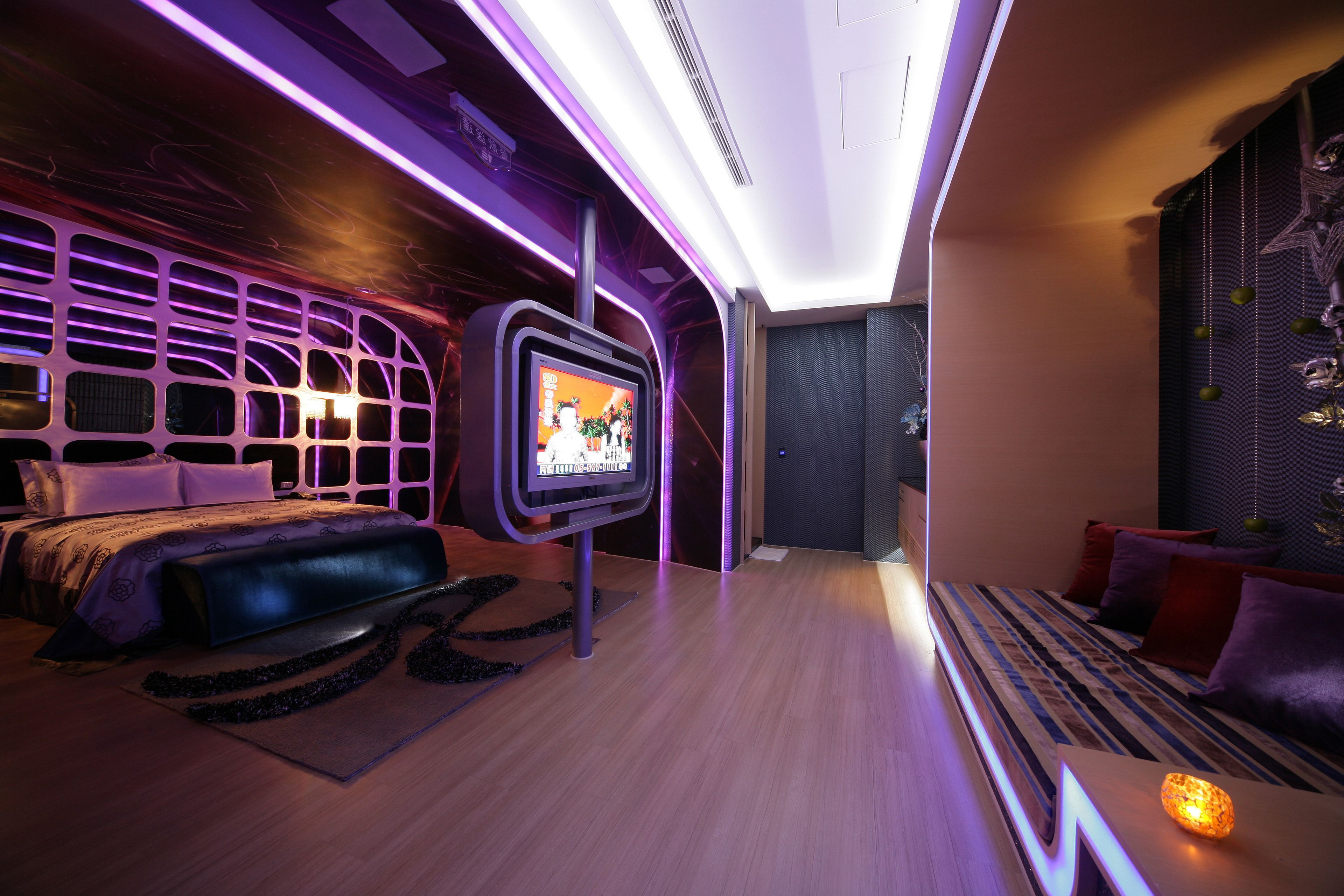 Een moderne slaapkamer met een groot bed, een televisie en sfeerverlichting.