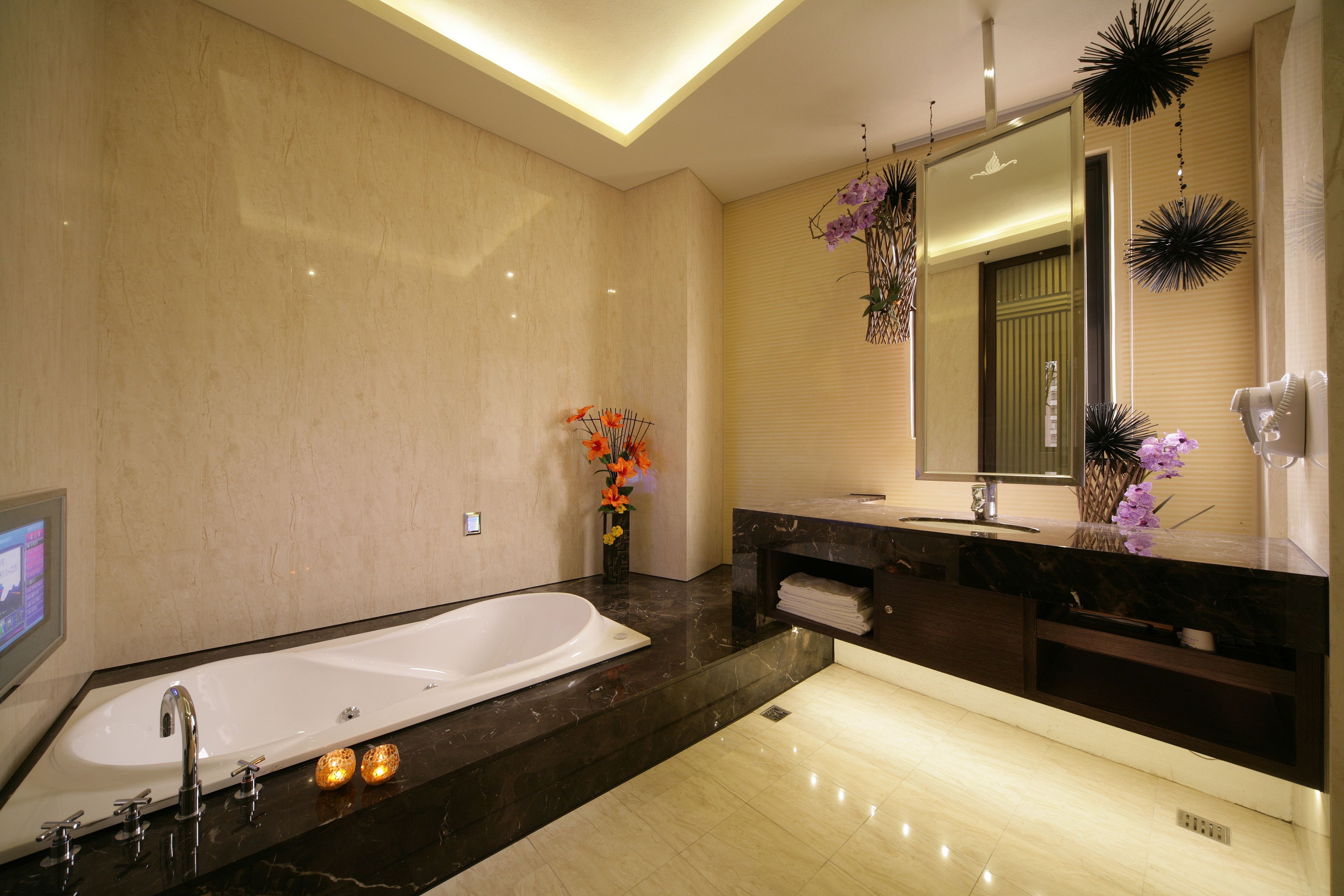 A modern bathroom with a large bathtub, a vanity with a mirror, and decorative plants.