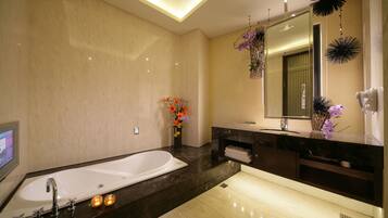 A modern bathroom with a large bathtub, a vanity with a mirror, and decorative plants.